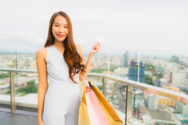 Bella giovane donna asiatica del ritratto felice e sorriso con il sacchetto della spesa dal grande magazzino