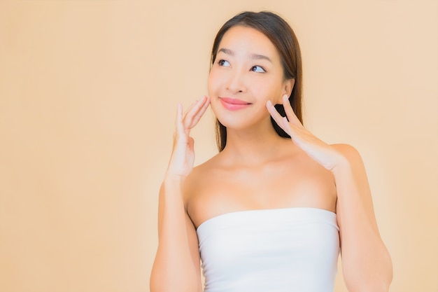 Bella giovane donna asiatica del ritratto nella stazione termale con trucco naturale sul beige