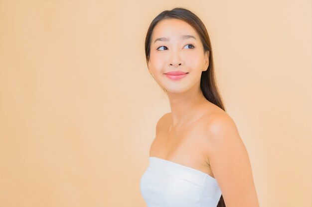 Bella giovane donna asiatica del ritratto nella stazione termale con trucco naturale sul beige