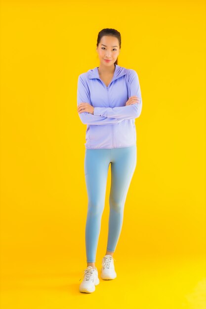 Bella giovane donna asiatica di sport del ritratto pronta per l'esercizio su giallo