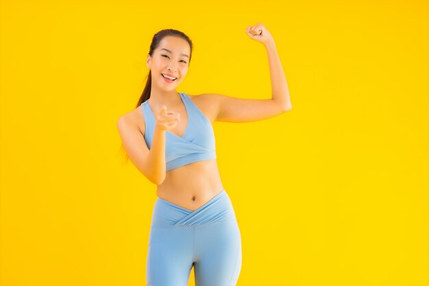 Bella giovane donna asiatica di sport del ritratto pronta per l'esercizio su giallo