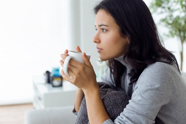 Bella giovane donna bere il caffè a casa.