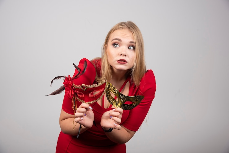 Foto gratuito bella giovane donna bionda in maschere rosse della tenuta del vestito.