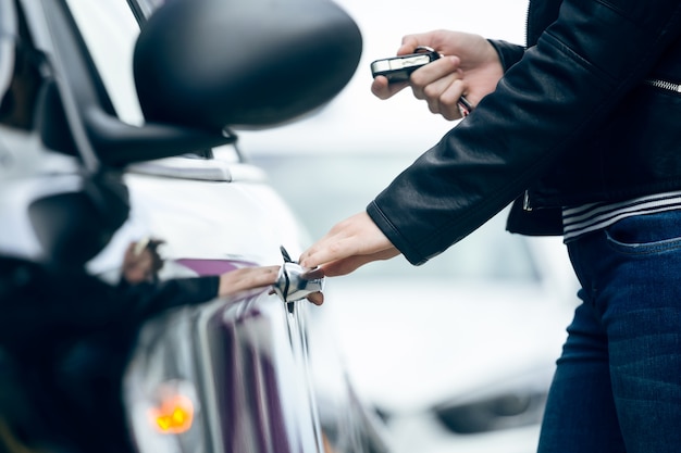 Bella giovane donna che apre la sua auto.