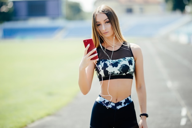 Bella giovane donna che ascolta la musica allo stadio