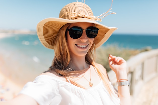 Bella giovane donna che fa selfie sulla spiaggia sull'oceano