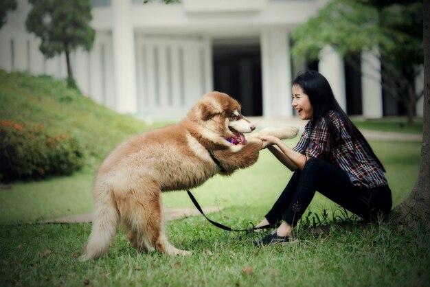 Bella giovane donna che gioca con il suo cagnolino in un parco all'aperto. Ritratto di stile di vita.