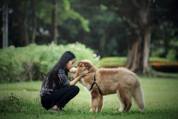 Bella giovane donna che gioca con il suo cagnolino in un parco all'aperto. Ritratto di stile di vita.