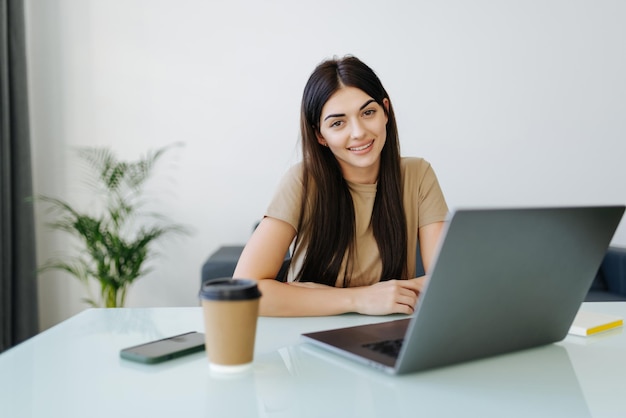 Bella giovane donna che lavora al suo computer portatile nel suo ufficio a casa