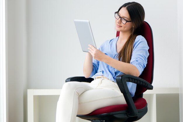 Bella giovane donna che lavora con il tablet digitale.