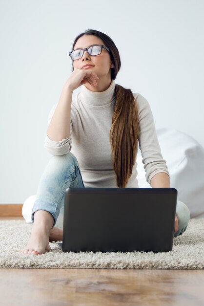 Bella giovane donna che lavora sul suo computer portatile a casa.