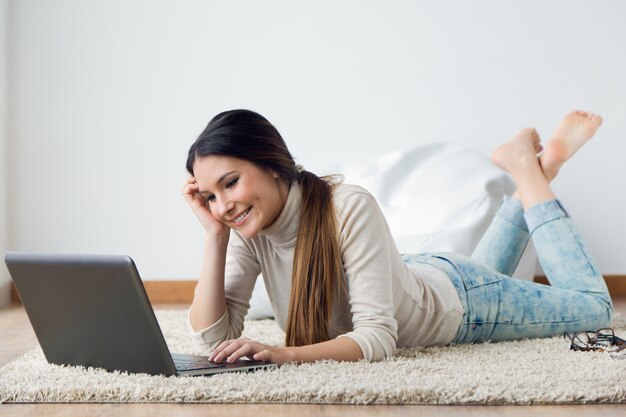 Bella giovane donna che lavora sul suo computer portatile a casa.