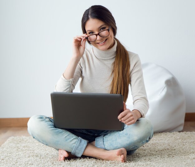 Bella giovane donna che lavora sul suo computer portatile a casa.