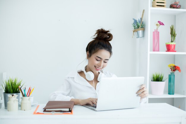 Bella giovane donna che lavora sul suo computer portatile nella sua stanza.