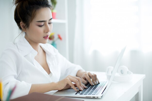 Bella giovane donna che lavora sul suo computer portatile nella sua stanza.