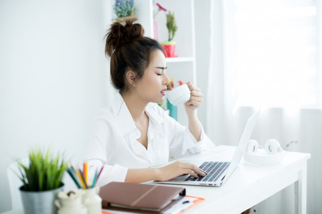 Bella giovane donna che lavora sul suo computer portatile nella sua stanza.