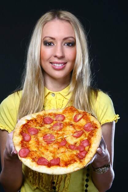Bella giovane donna che mangia pizza