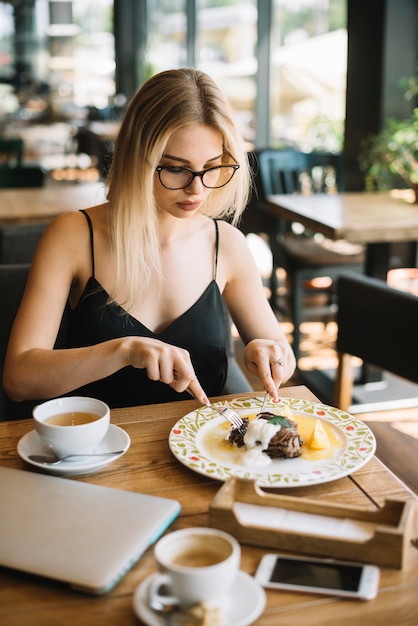 Bella giovane donna che mangia prima colazione nel caf���