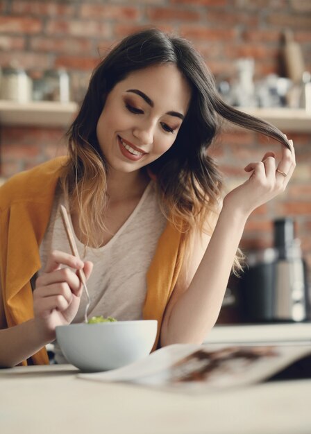 Bella giovane donna che mangia un'insalata sana