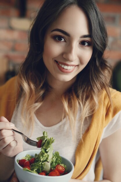 Bella giovane donna che mangia un'insalata sana