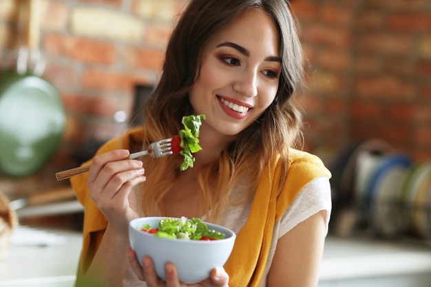 Bella giovane donna che mangia un'insalata sana