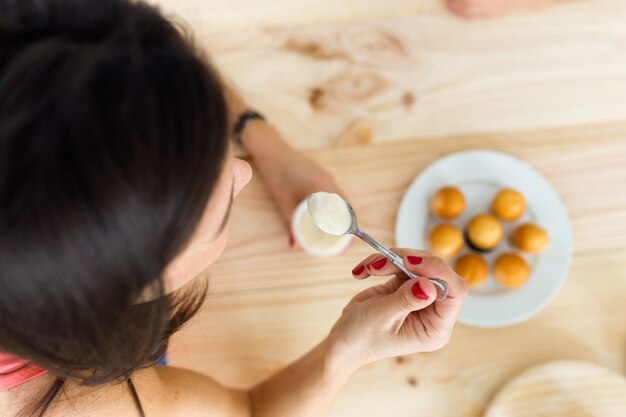 Bella giovane donna che mangia yogurt a casa.