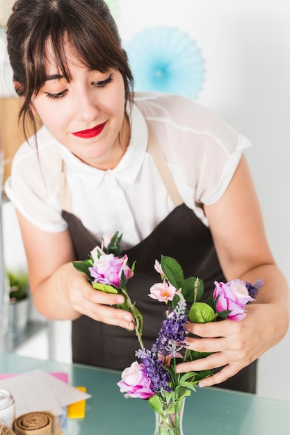 Bella giovane donna che mette i fiori in vaso