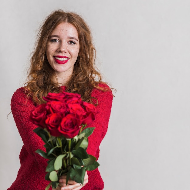 Bella giovane donna che offre un mazzo di rose