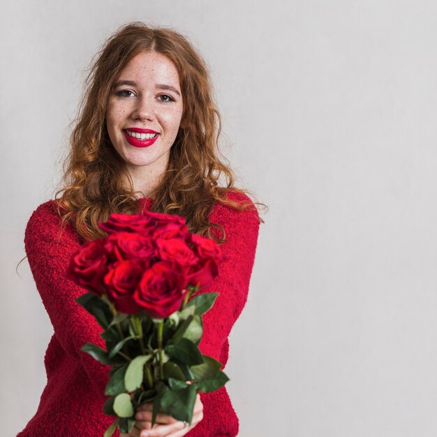 Bella giovane donna che offre un mazzo di rose
