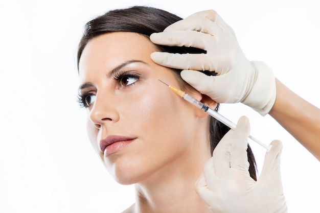 Bella giovane donna che ottiene l&#39;iniezione cosmetica di botox in faccia.