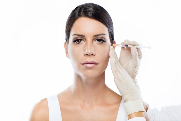 Bella giovane donna che ottiene l&#39;iniezione cosmetica di botox in faccia.