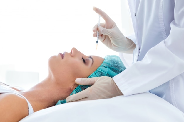 Bella giovane donna che ottiene l&#39;iniezione cosmetica di botox in faccia.