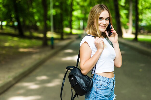 Bella giovane donna che parla su un telefono nel parco di estate della città.