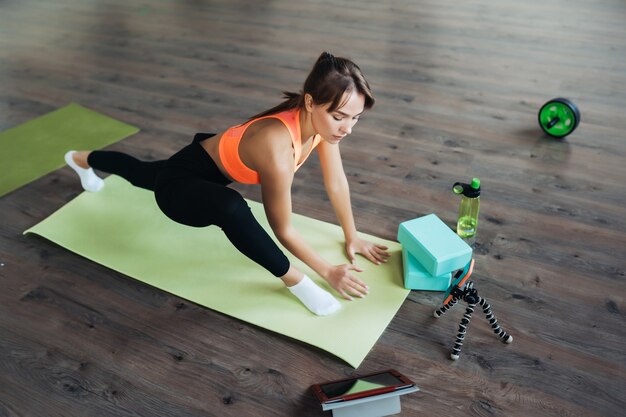 Bella giovane donna che pratica yoga, è impegnata con l'insegnante online tramite un tablet. Concetto di sport domestico.