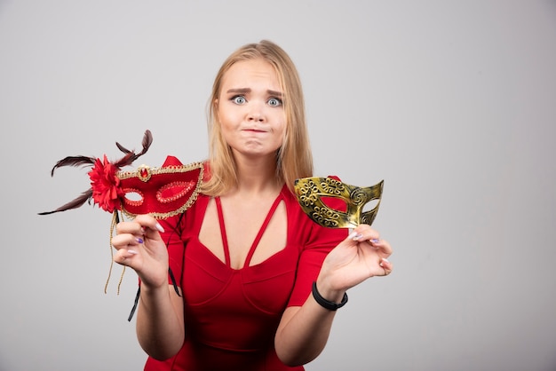 Bella giovane donna che tiene le maschere veneziane dorate misteriose.