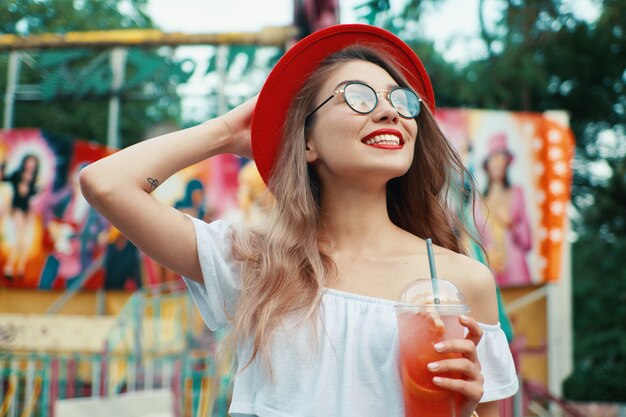 Bella giovane donna che tiene un drink mentre sorridendo