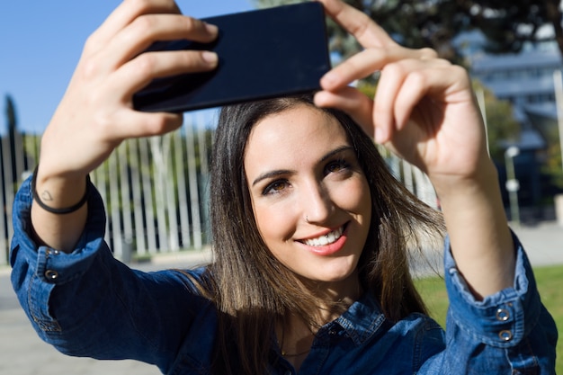 Bella giovane donna che utilizza il suo cellulare in strada.