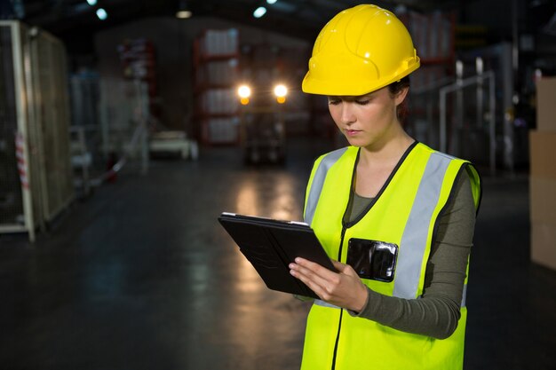 Bella giovane donna che utilizza tablet pc in fabbrica