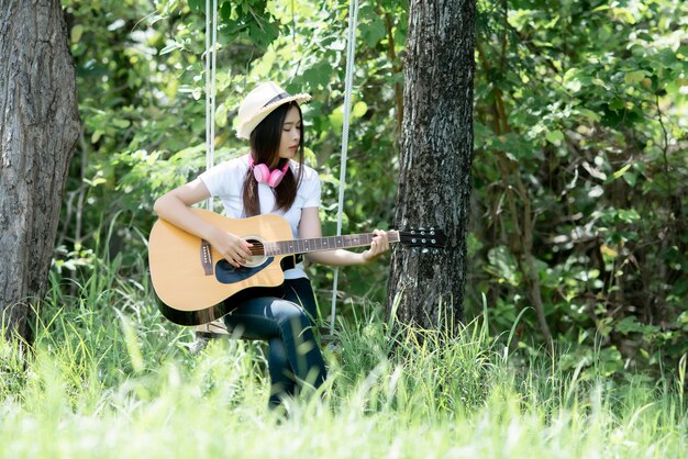 Bella giovane donna con chitarra acustica in natura