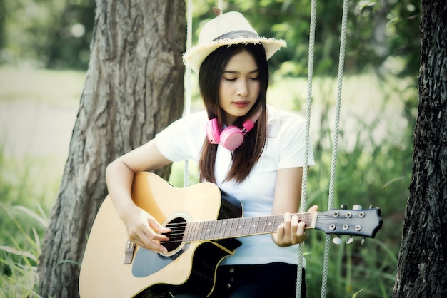 Bella giovane donna con chitarra acustica in natura