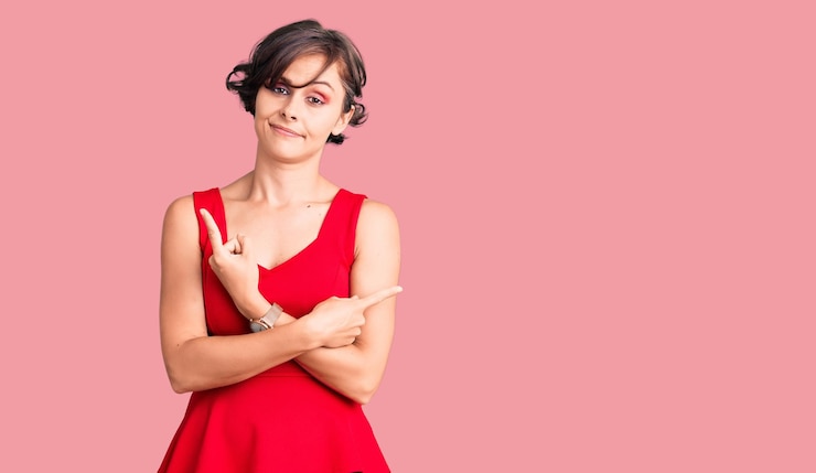 Foto gratuito bella giovane donna con i capelli corti che indossa uno stile casual con camicia senza maniche che punta su entrambi i lati con le dita in direzioni diverse non sono d'accordo