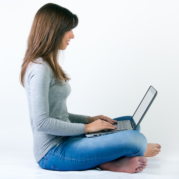 Bella giovane donna con il computer portatile in studio