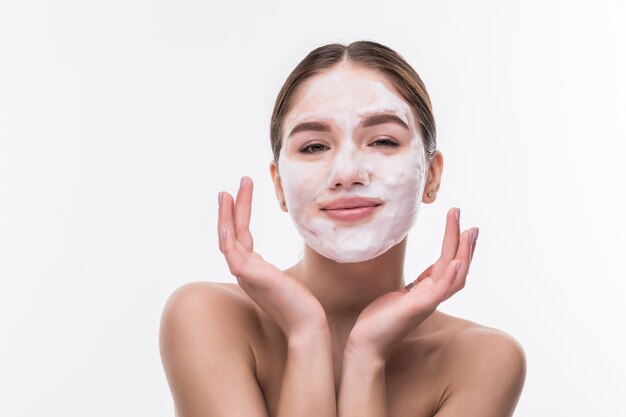 Bella giovane donna con la maschera facciale sulla parete bianca