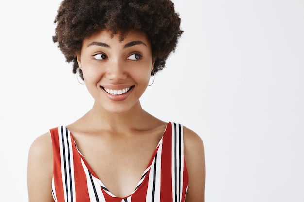 bella giovane donna dalla carnagione scura felice e gioiosa con acconciatura afro guardando con ampio sorriso a destra