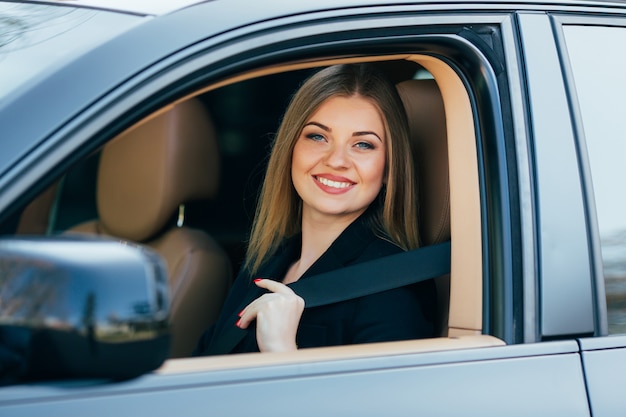 Bella giovane donna felice allaccia una cintura di sicurezza in macchina