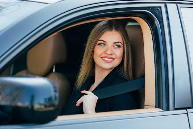 Bella giovane donna felice allaccia una cintura di sicurezza in macchina