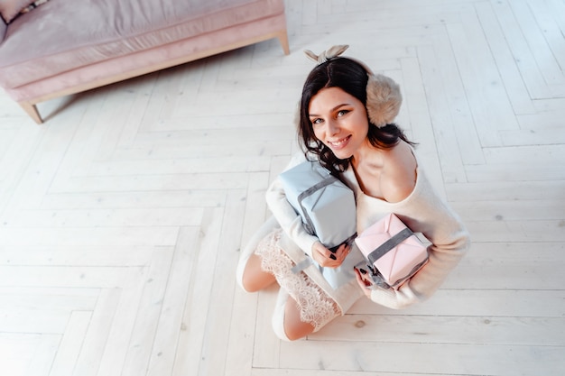 Bella giovane donna in abito bianco in posa con scatole regalo