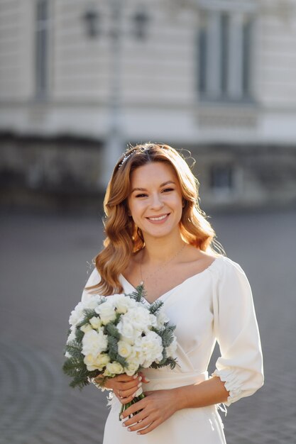 Bella giovane donna in abito da sposa in posa sulla strada in città