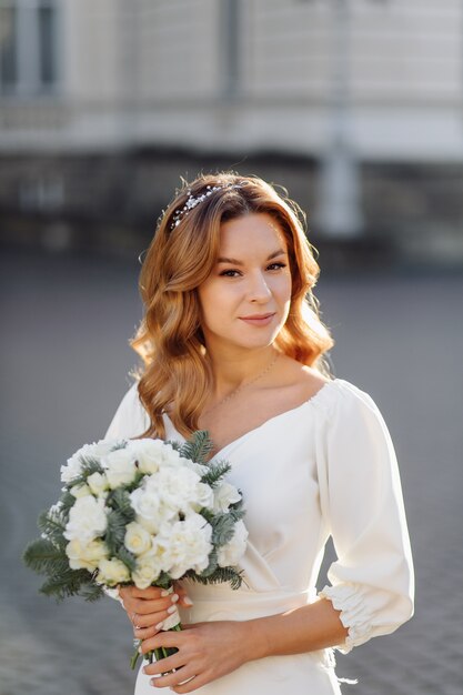 Bella giovane donna in abito da sposa in posa sulla strada in città