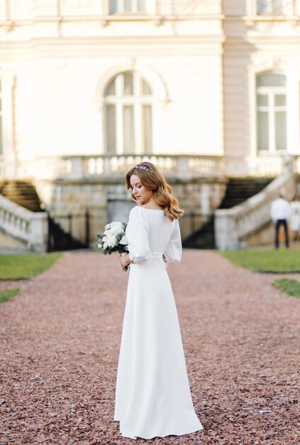 Bella giovane donna in abito da sposa in posa sulla strada in città